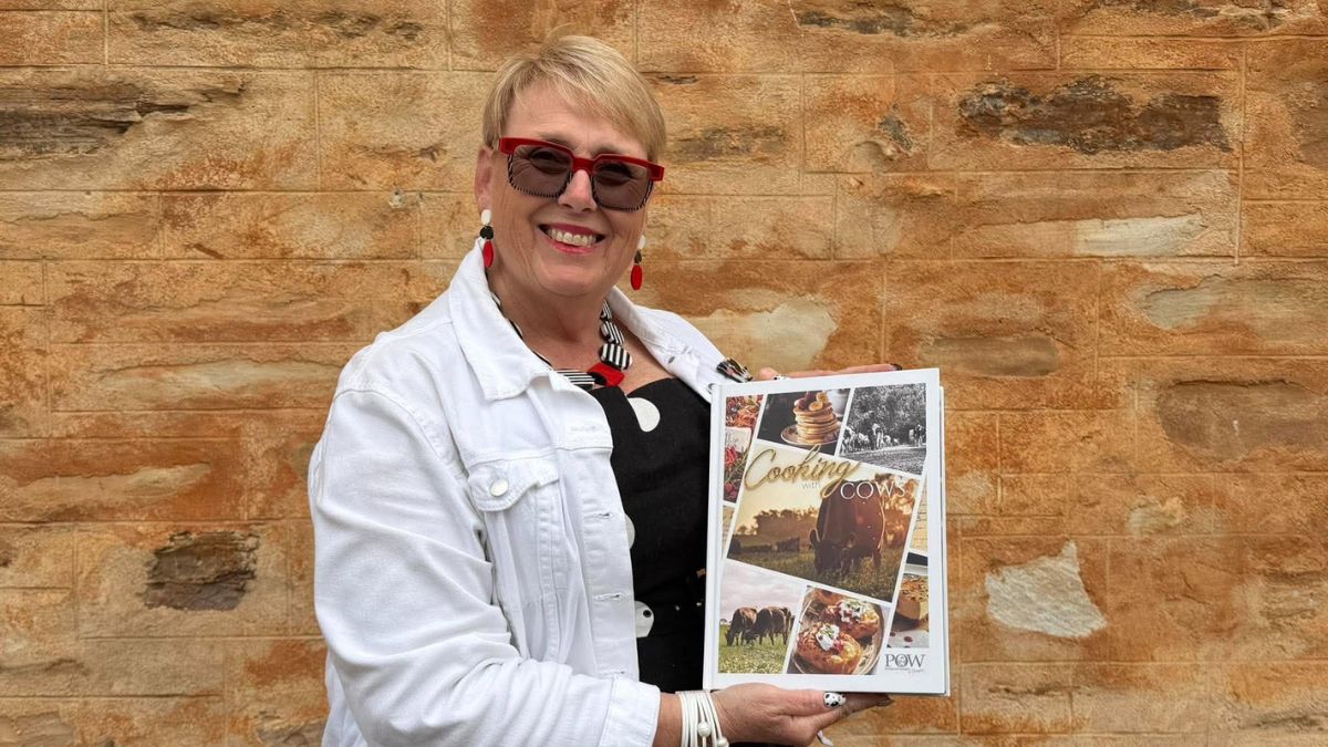 Fleurieu Peninsula dairy farmer Mandy Pacitti holding a copy of Cooking with Cows.